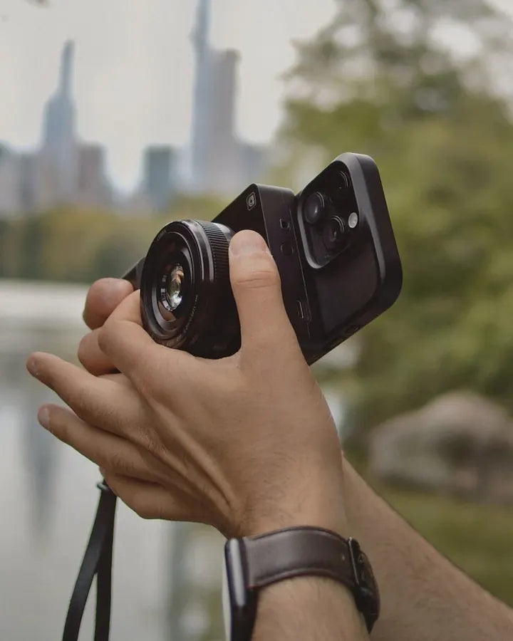 Caira and iPhone held up in Central Park, Manhattan skyline behind
