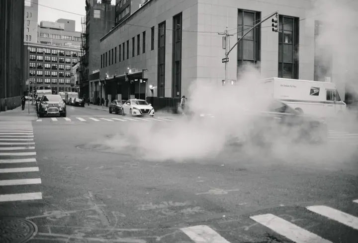 LUMIX G 20/F1.7 II · 19mm · ISO 400 · 1/76s · f/1.8 Steam drifting across a black-and-white New York intersection, captured with Caira
