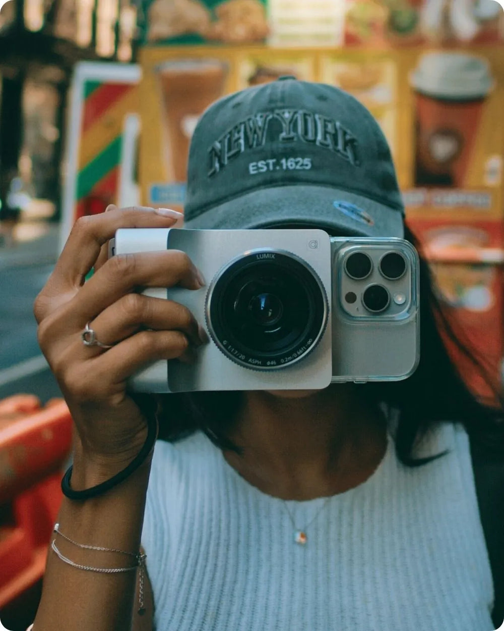 A woman in a New York cap taking a photo with Caira on her iPhone
