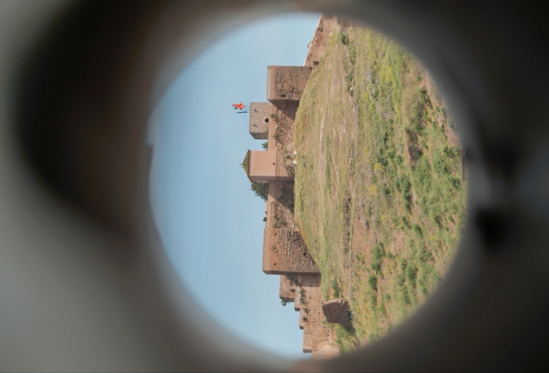 Hilltop castle framed through a circular viewing scope — captured with Caira