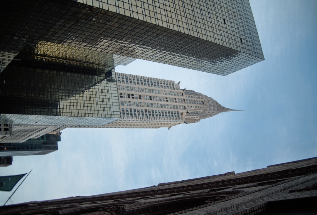 Chrysler Building framed by glass towers, looking up — captured with Caira