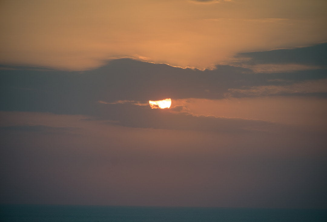 Sunset behind a band of cloud over the sea, captured with Caira