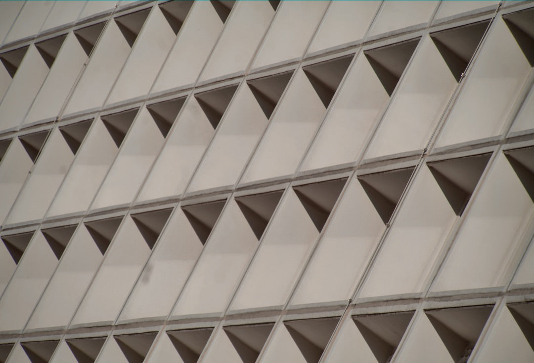 Repeating triangular window pattern on a modernist facade — captured with Caira