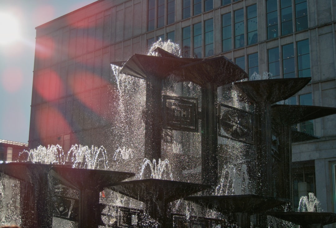Sunlit fountain at Alexanderplatz with visible lens flare