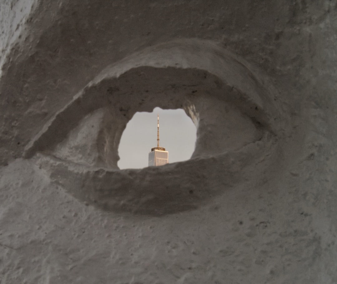 Skyscraper seen through the eye of a carved white sculpture