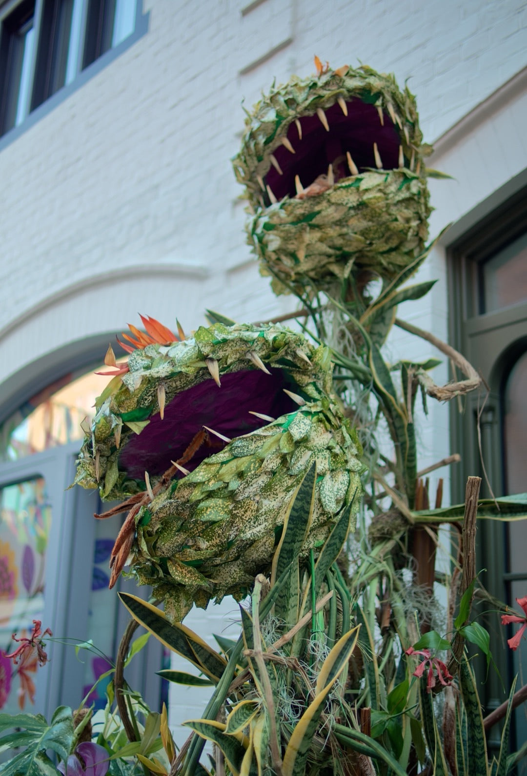 Venus-flytrap garden sculpture outside a brick house