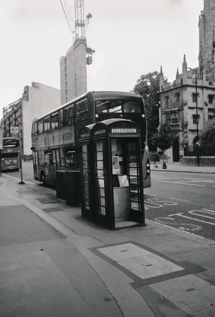 Black-and-white London street scene with a telephone box and double-decker bus, captured with Caira