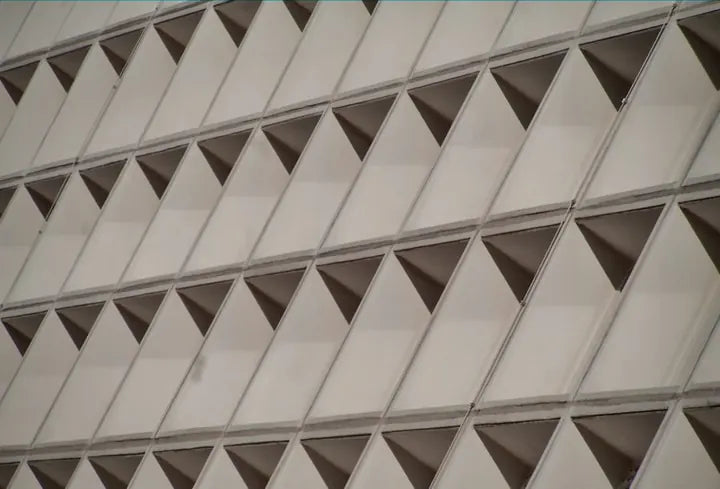 Repeating triangular window pattern on a modernist facade, captured with Caira