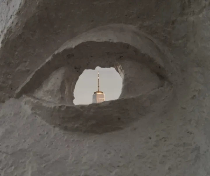 Skyscraper seen through the eye of a carved white sculpture, captured with Caira