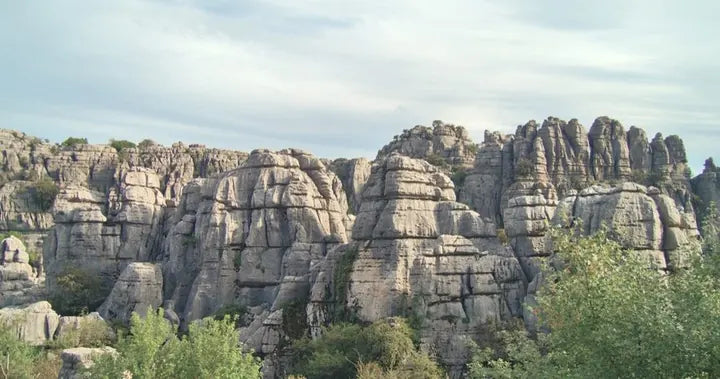Layered limestone rock formations under a soft sky, captured with Caira